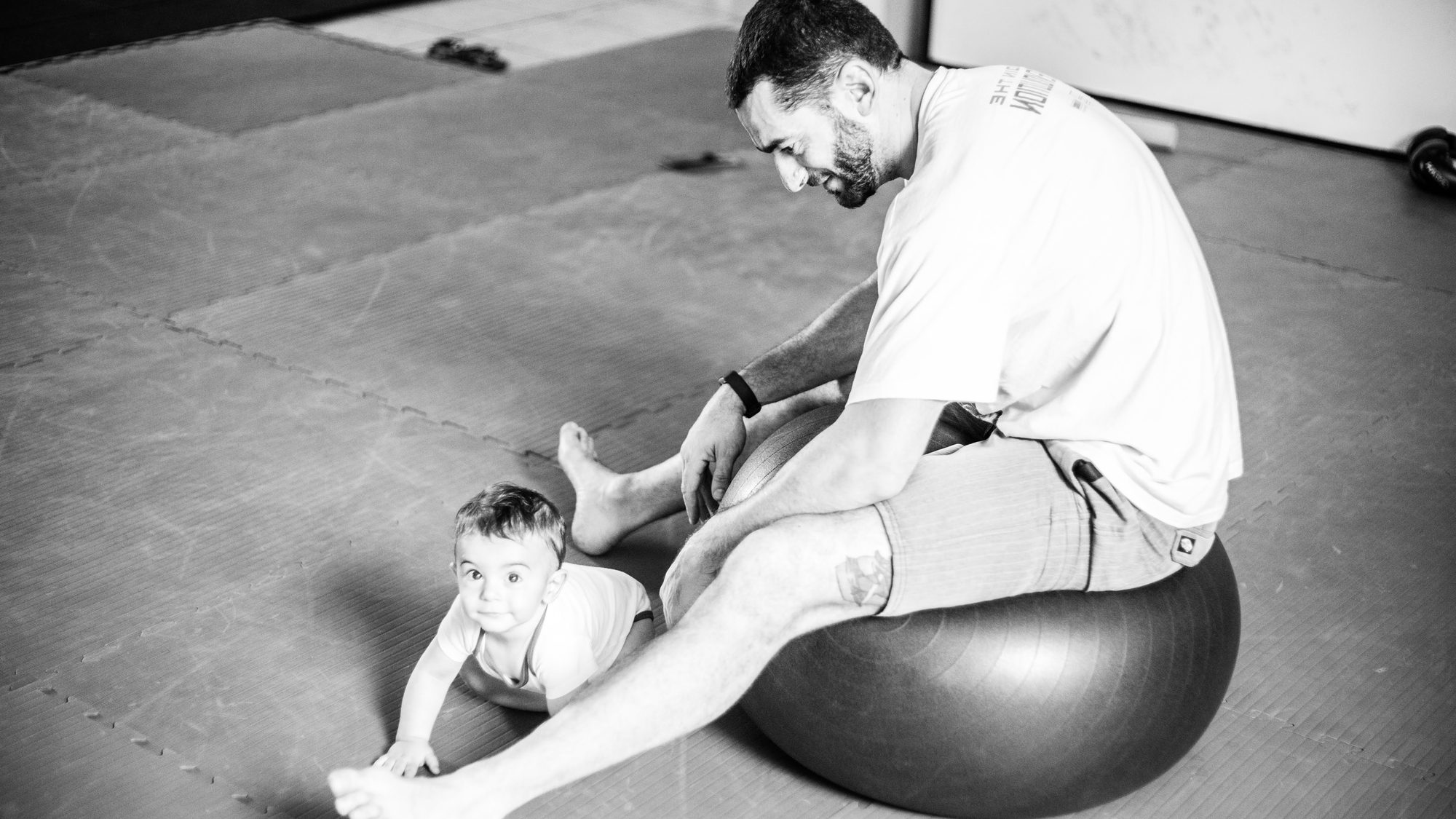 Emanuele si allena sul tappeto della palestra con il figlio piccolo accanto